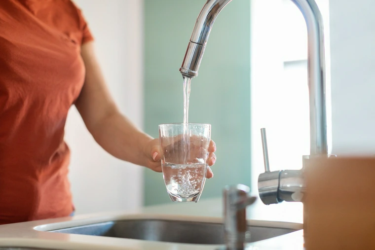 someone pouring water from the faucet into a glass